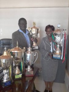 MR NASONGO AND MRS NABISWA DISPLAY THE FIVE CHOIR NATIONAL TROPHIES WON IN 2017